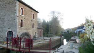 Vue du moulin avec sa roue en bordure de la Vilaine longée par le chemin de halage