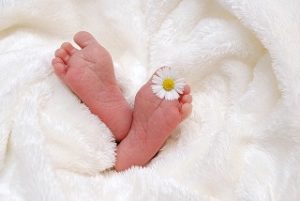 Les 2 pieds d'un bébé sortant de la couette